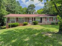 Charming one-story brick home featuring a well-maintained lawn and mature trees at 2000 Stone Mountain Lithonia Rd, Lithonia, GA 30058