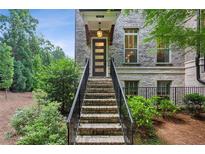 Brick townhouse exterior featuring a modern front door, landscaped yard, and inviting stairway at 4355 Parkside Pl, Sandy Springs, GA 30342