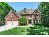 Beautiful brick home with a well-manicured lawn, a two car garage, and mature trees at 140 Longwater Cv, Roswell, GA 30075