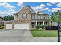 Charming brick two-story home with a manicured front lawn, three car garage, and covered front porch at 4191 Secret Shoals Way, Buford, GA 30518