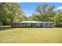 Charming single-story home with a metal roof, brick accents, manicured landscaping, and a large front yard at 4715 Howard Dr, Powder Springs, GA 30127