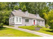 Charming grey brick home featuring a red front door, dormer windows, and a well-manicured lawn at 6596 Wright Ne Rd, Atlanta, GA 30328