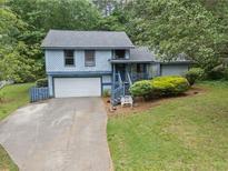 Charming two-story home featuring a front yard, attached garage, and mature trees at 9760 Loblolly Ln, Roswell, GA 30075