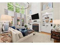 Bright living room featuring high ceilings, large windows, fireplace and stylish furniture at 4905 Village Green Dr, Roswell, GA 30075
