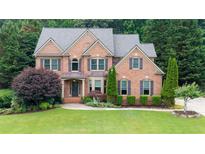 Charming brick home with a well-manicured lawn, mature trees, and traditional architectural details at 161 Highgrove Dr, Suwanee, GA 30024