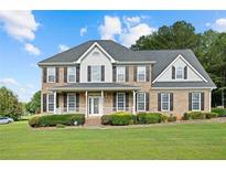 Charming two-story home with a well-manicured lawn, covered porch, brick facade, and lush landscaping at 327 Awendaw Cir, Ellenwood, GA 30294