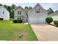 Charming two-story home features a stone accent facade, a well-manicured lawn, and a two-car garage at 4041 Ash Tree St, Snellville, GA 30039