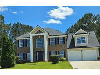 Beautiful two-story brick home with well-manicured lawn and attached two-car garage at 681 Burtons Cv, Hampton, GA 30228