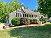 Charming single-Gathering home featuring well-maintained landscaping, inviting front porch, and mature trees at 148 Paradise Xing, Douglasville, GA 30134