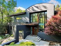 Striking modern home featuring a unique curved roofline and expansive windows, surrounded by lush greenery at 265 Tara Trl, Atlanta, GA 30327