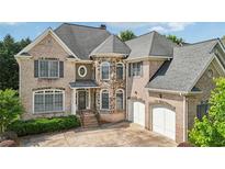 Charming brick home featuring a manicured lawn, multiple windows, and an attached two-car garage at 2871 Trailing Ivy Way, Buford, GA 30519