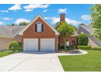Charming brick home featuring a two-car garage, manicured lawn, and beautiful landscaping at 980 Windsor Place Cir, Grayson, GA 30017