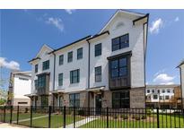 Charming townhome showcasing white painted brick, black trim, and a well-manicured lawn secured by a black metal fence at 502 Healy Dr # 76, Cumming, GA 30040