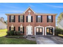 Two-story brick home with black shutters and a manicured front lawn offers classic charm at 9066 Bob Jackson Dr, Jonesboro, GA 30238