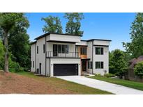 Modern two-story home with white exterior, black trim, balcony, and a driveway leading to an attached garage at 1610 Niskey Lake Rd, Atlanta, GA 30331