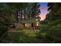 Charming single-story brick home featuring an attached carport and lush, mature landscaping at dusk at 2595 Woodhill Cir, Atlanta, GA 30344