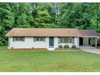 Charming brick home features a manicured lawn, updated windows, and a convenient carport at 5689 Woodland Dr, Acworth, GA 30102