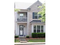 Charming two-story home with brick facade, gray siding, and a welcoming front porch with balcony at 7699 Cabrini Pl, Fairburn, GA 30213