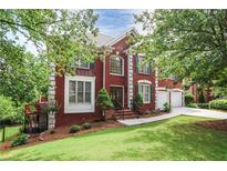 Beautiful two-story brick home with a well-manicured lawn and mature trees at 740 Creek Wind Ct, Duluth, GA 30097