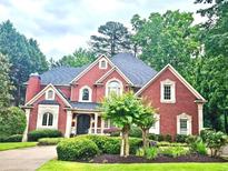 Stunning two-story brick home boasts manicured landscaping, elegant architectural details, and a welcoming front entrance at 8250 Saint Marlo Fairway Dr, Duluth, GA 30097