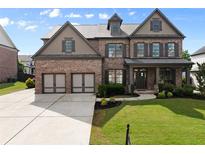 Beautiful brick home featuring a manicured lawn, two-car garage, and covered front porch at 3317 Sweetleaf Ln, Buford, GA 30519