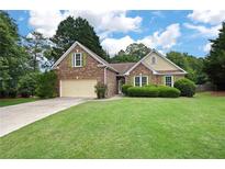 Charming brick home with a well-manicured lawn and mature trees at 4801 Devonhurst Way, Powder Springs, GA 30127