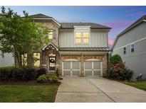 Charming two-story home with brick and siding, a two-car garage, and a well-manicured lawn at 935 Grove Valley Drive Dr, Cumming, GA 30041