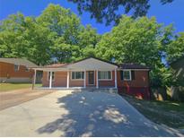 Charming brick home featuring a covered front porch with classic column detailing and a wide driveway at 1150 Goldsmith Rd, Stone Mountain, GA 30083