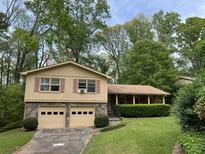 Split level home with neutral siding, garage, stone accents, and mature trees at 3511 Brookview Dr, Marietta, GA 30068