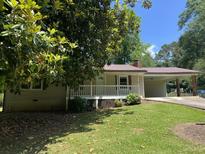 Charming home featuring a covered carport and a cozy front porch surrounded by lush greenery at 6512 Executive Dr, Winston, GA 30187
