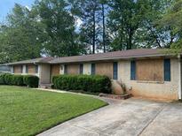 Ranch-style home with brick facade, mature landscaping, and boarded-up windows at 1692 Pheasant Dr, Jonesboro, GA 30238