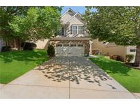 Charming home featuring an attached two car garage, with mature trees in the front yard at 2040 Harvest Ridge Cir, Buford, GA 30519