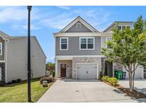 Charming townhouse featuring a one-car garage and a welcoming facade with gray siding and brick accents at 1884 Plainsboro Drive Dr, Lithonia, GA 30058