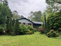 Charming single-story home surrounded by lush greenery and mature trees, creating a private and serene setting at 7235 Thornhill Ne Ln, Atlanta, GA 30328