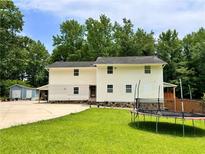 Spacious backyard with a two-story home featuring white siding, a trampoline, and a lush lawn at 7326 Leland Ln, Jonesboro, GA 30236