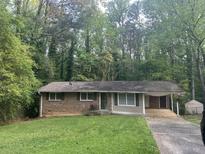 Charming single-story home with brick accents, covered parking and a well-maintained lawn surrounded by mature trees at 971 Canyon Sw Trl, Marietta, GA 30060