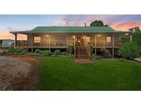 Charming home featuring a green roof, spacious porch with wooden railings, and lovely landscaped front yard at 220 Mountain Creek Rd, Bowdon, GA 30108