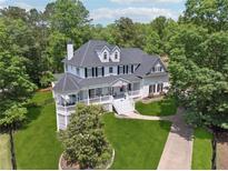 Stunning two-story home boasts a charming white exterior, inviting front porch, and lush landscaping at 471 Henderson Lake Dr, Canton, GA 30115