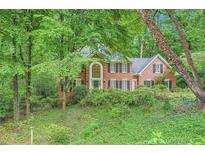 Charming two-story brick home with lush landscaping and mature trees offering privacy at 8470 Valemont Dr, Atlanta, GA 30350