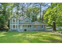 Charming two-story home with a well-manicured lawn, lovely front porch, and beautiful mature trees at 800 Post Road Cir, Stone Mountain, GA 30088