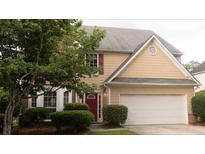 Charming two-story home with a two-car garage, red door, manicured lawn, and mature trees at 3292 Shady Valley Ct, Loganville, GA 30052