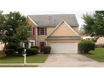 Charming two-story home featuring a well-manicured lawn, a two-car garage, and a welcoming red front door at 3292 Shady Valley Ct, Loganville, GA 30052