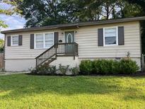 Charming single-story home featuring a well-maintained lawn, complemented by verdant greenery and a welcoming front entrance at 633 Tom Read Dr, Marietta, GA 30062