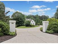 Long driveway leading to a beautiful home with manicured landscaping and a classic white exterior at 590 Arthur Rd, Canton, GA 30115