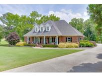 Stately red brick home featuring a well-manicured lawn and a curved driveway, creating a welcoming curb appeal at 2623 Lindsey Grace Ln, Buford, GA 30519