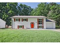 Charming, renovated single-story home with white painted brick, red door, brown shutters and a well-manicured lawn at 1349 Heather Cir, Riverdale, GA 30296