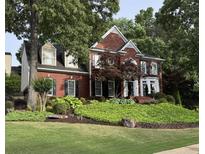 Charming two-story brick home featuring lush landscaping, a manicured lawn, and traditional architectural details at 750 Highview Ct, Woodstock, GA 30189