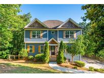 Charming two-story home featuring a blue exterior, shingled accents, lush landscaping, and a curved driveway at 1496 Shadowrock Dr, Marietta, GA 30062