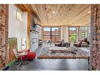 Open living room with wood ceiling, brick accents, and modern fireplace features oversized windows for natural light at 87 Peachtree Sw St # 209, Atlanta, GA 30303