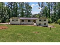 Charming ranch home featuring a lush lawn and mature trees, creating a serene and inviting atmosphere at 145 Devilla Trce, Fayetteville, GA 30214